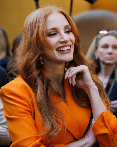 Jessica Chastain smiling in an orange blazer